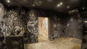 Una habitación con un diseño artístico único en la pared, un ventanal grande y un espacio para sentarse.