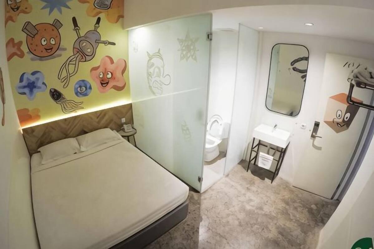 A bedroom with a bed, a bathroom with a toilet and sink, and a mirror.