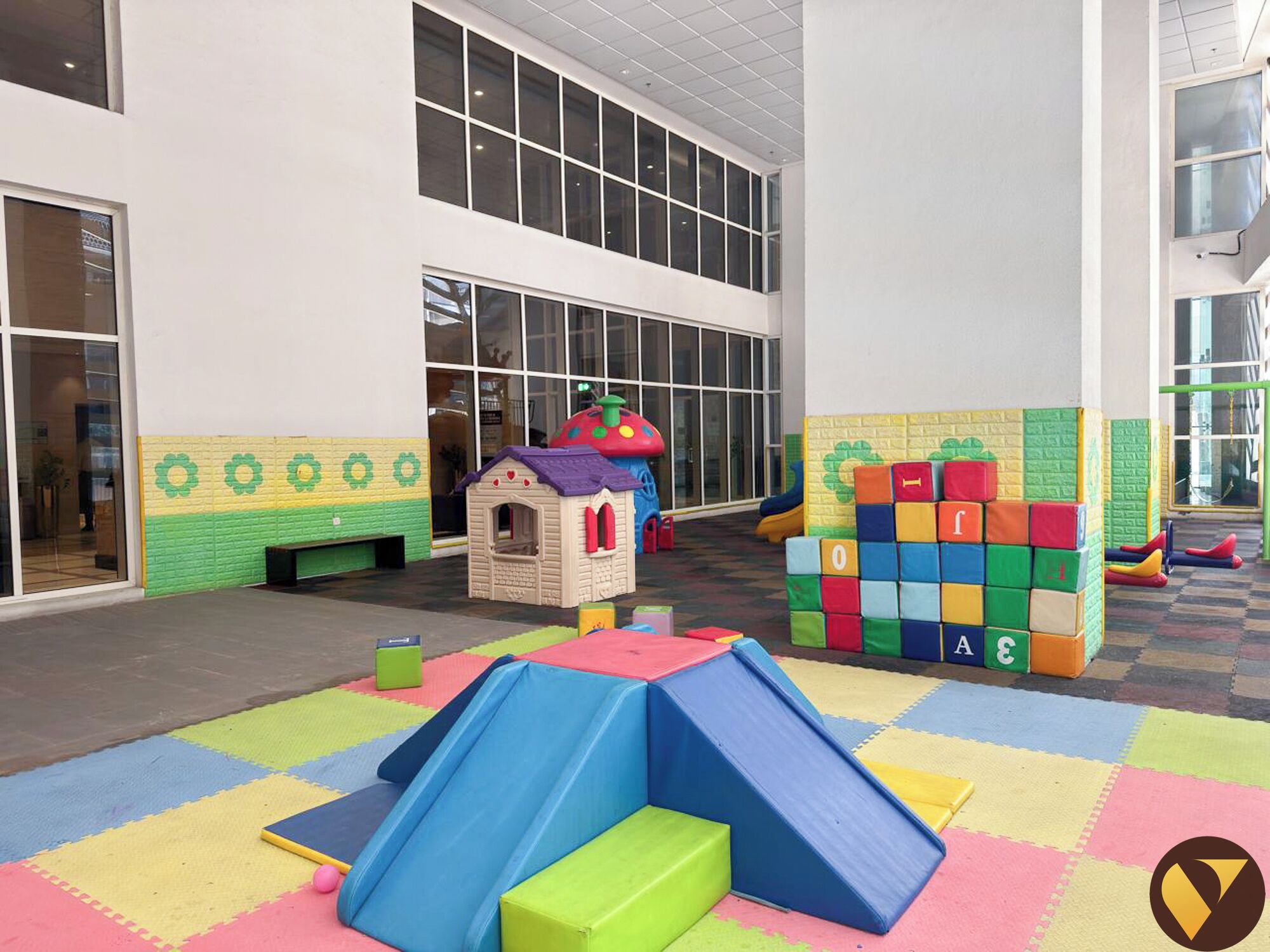 Zona infantil con un tobogán, bloques de espuma y una casita.