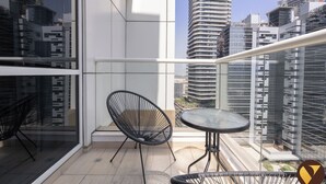 A balcony with a glass railing, two black chairs, and a small round table. - Vogue | Mon Reve near Dubai Mall | Burj Khailfa (Dubai)