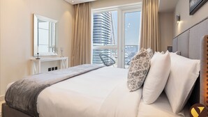 A hotel room with a large bed, a mirror, a window with curtains, and a view of a building. - Vogue | Mon Reve near Dubai Mall | Burj Khailfa (Dubai)