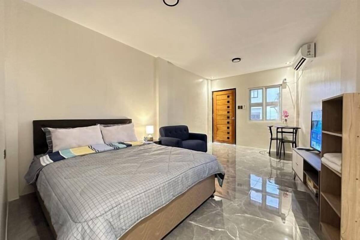 A bedroom with a bed, a chair, a desk, and a TV.