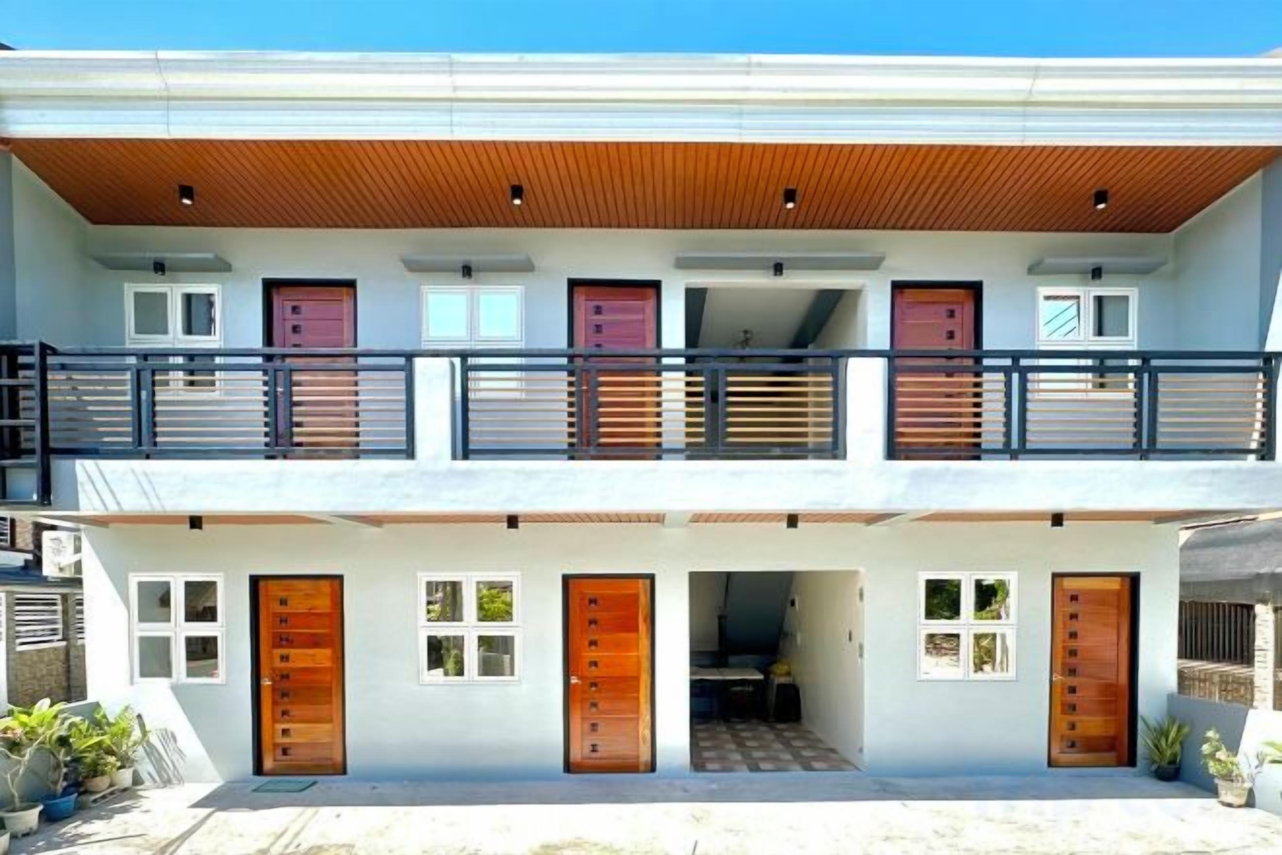 A two-story building with a balcony, multiple doors, and a covered entrance.