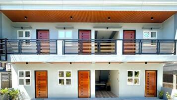 A two-story building with a balcony, multiple doors, and a covered entrance.