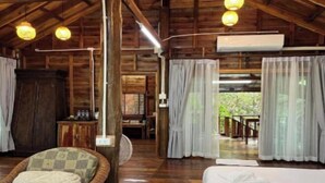 Ein Holzblockhaus-Interieur mit einem Bett, einem Korbsessel und einem Essbereich.