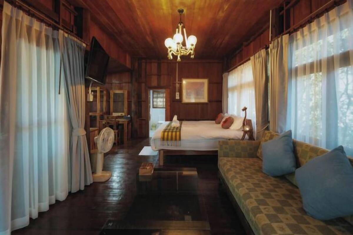 Een kamer met een bed, een bank, een televisie en een kroonluchter.