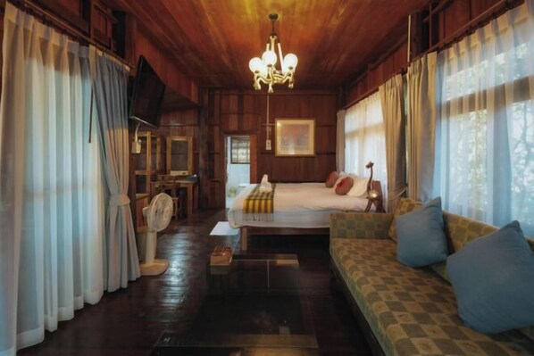 Ein Zimmer mit einem Bett, einem Schlafsofa, einem Fernseher und einer Chandelüstere.