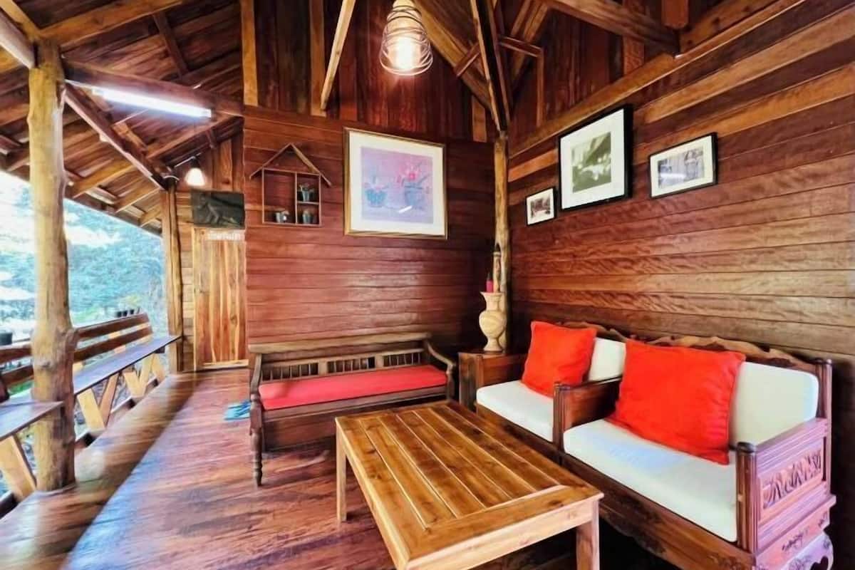 Een houten blokhut van binnen met een houten bank, een bank en een tafel.