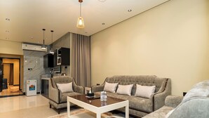 Un salon moderne avec un ensemble de canapés, une table basse et un coin cuisine à l’arrière-plan.