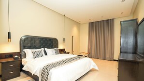 Une chambre moderne avec un grand lit, des tables de chevet, une télévision et une armoire.
