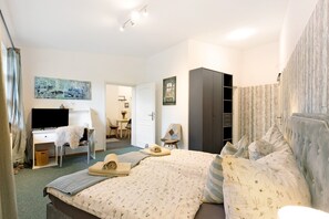 A hotel room with a bed, a desk, a chair, a wardrobe, and a television.