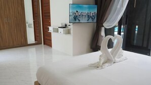 Une chambre d’hôtel avec un lit, une télévision, une étagère fixée au mur et une grande fenêtre avec des rideaux.