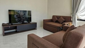 Un salon moderne avec un canapé marron, un téléviseur à écran plat posé sur une console en bois et une petite table d’appoint sur laquelle se trouve un vase.