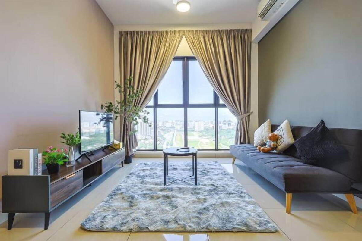 Una sala de estar moderna con un ventanal grande, un sofá, una mesa de centro y un televisor sobre un mueble de madera.