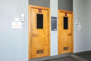Dos puertas de madera con rejas de ventilación, un detector de incendios y un tablón de anuncios.