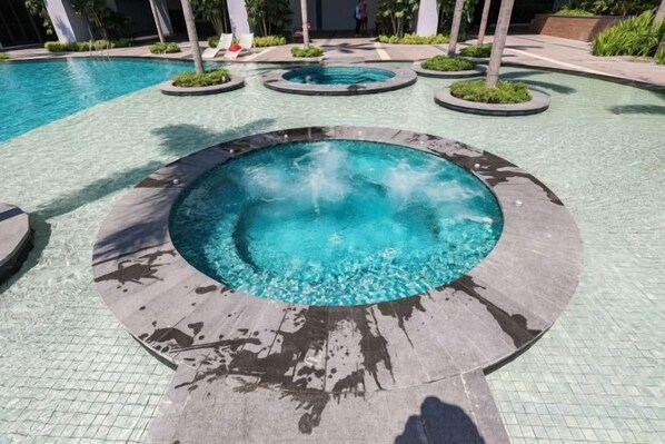 A swimming pool with a circular hot tub and a tiled deck area. - Trion KL by Vivid Stay (Kuala Lumpur)