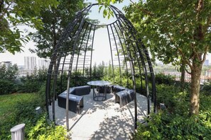 A gazebo with a circular table and seating, surrounded by greenery. - Trion KL by Vivid Stay (Kuala Lumpur)