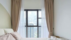 Une chambre d’hôtel avec une grande fenêtre, un lit et des rideaux.