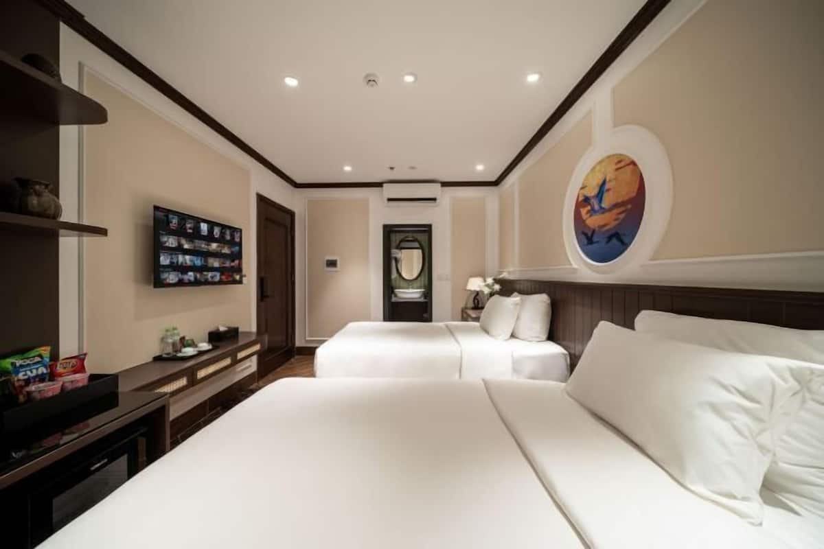 Habitació d'hotel amb dos llits, televisió de pantalla plana, un quadre i un minibàr.