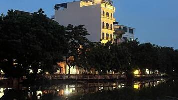 A building with a prominent tower, a reflection in the water, and trees in the foreground.
