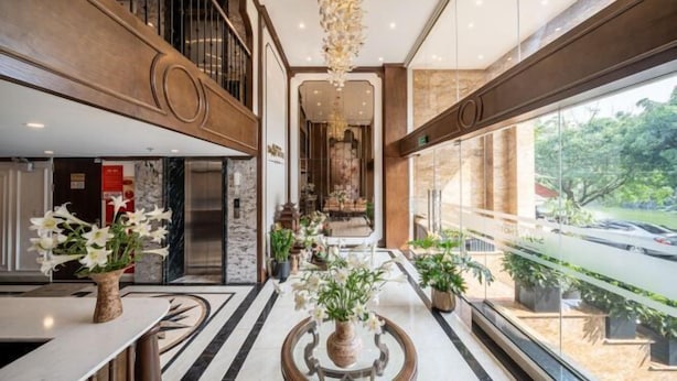 A spacious lobby with a high ceiling, a central seating area with a round table, and a view of the outside through large windows. - Legend Smart Hotel (Hanoi)