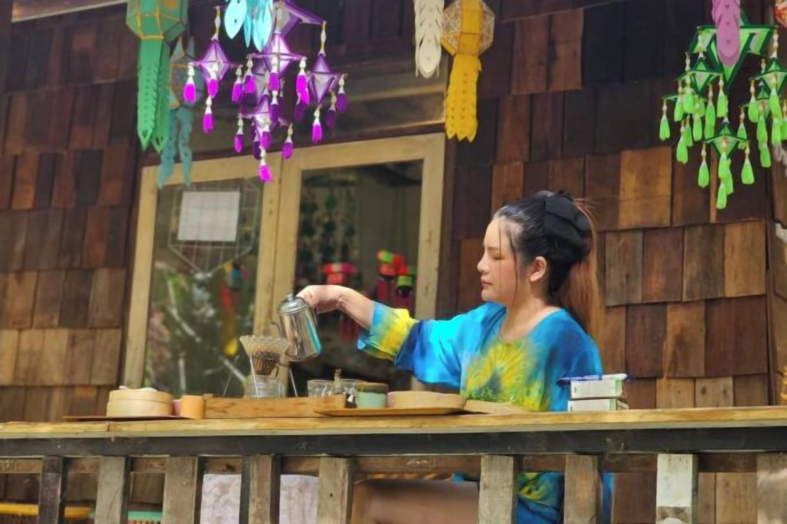 A person pouring a liquid from a can into a glass on a wooden table.