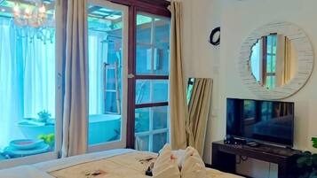 A hotel room with a bed, a television, and a sliding glass door leading to an outdoor area.