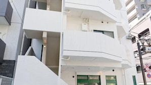 Un edificio de varios pisos con paredes exteriores blancas, balcones y una puerta verde.