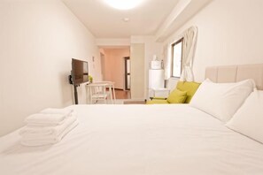 A hotel room with a bed, a desk, a television, and a window with curtains.