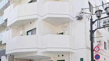 A multi-story building with balconies, a no parking sign, and a street lamp.