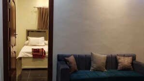 A room with a bed, a dark-colored sofa, and a small table. - Susan's Guest House and Tours (Luxor)