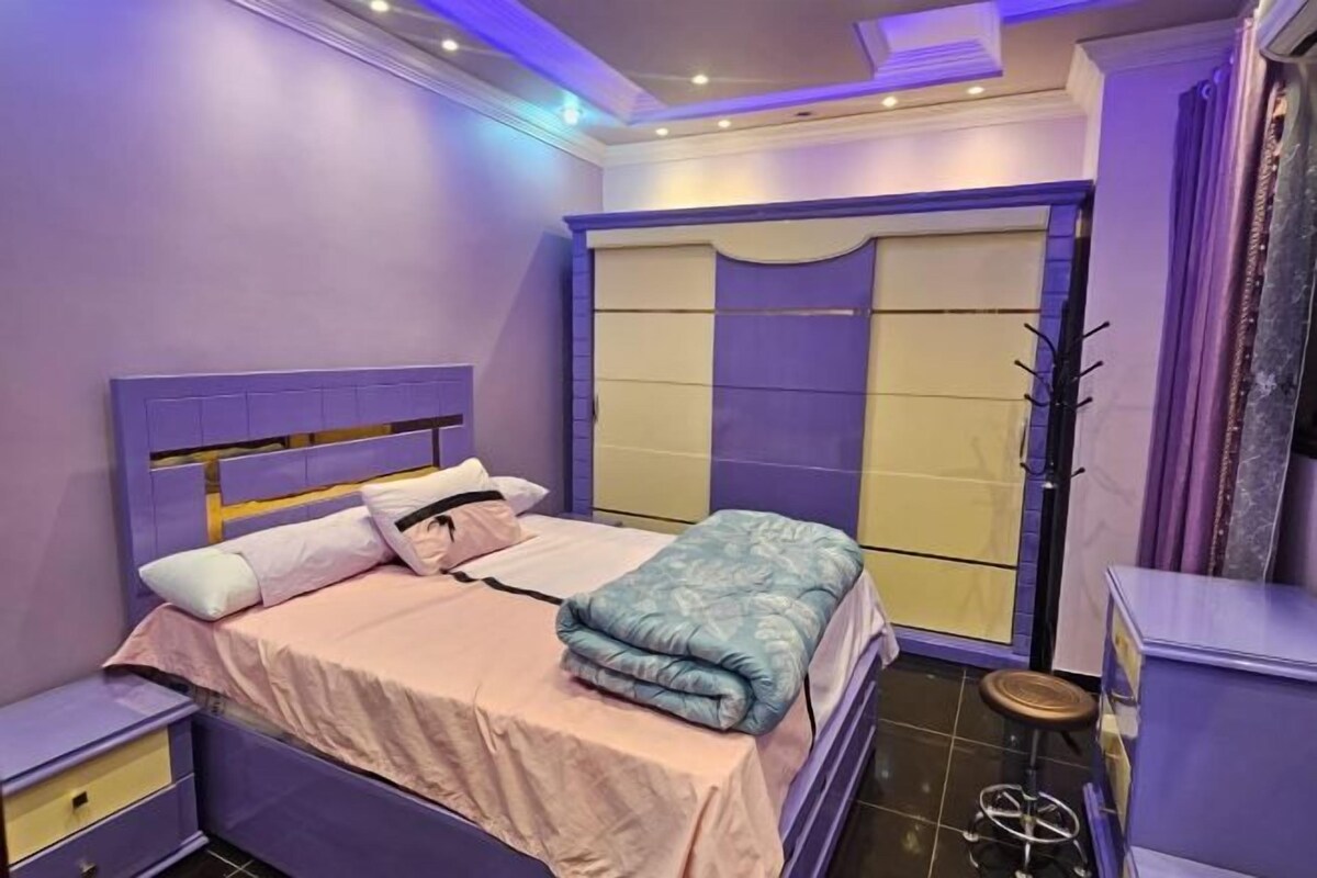 A bedroom with a bed, nightstands, a wardrobe, and a stool.