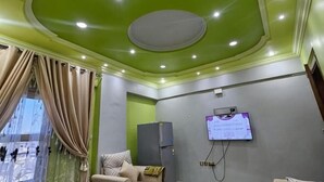 A room with a green ceiling, a bed, a desk, and a wall-mounted TV. - Susan's Guest House and Tours (Luxor)