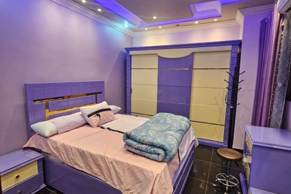 A bedroom with a bed, nightstands, a wardrobe, and a stool.