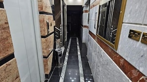 A narrow hallway with black and white marble flooring, a trash bin, and a door at the end. - Susan's Guest House and Tours (Luxor)