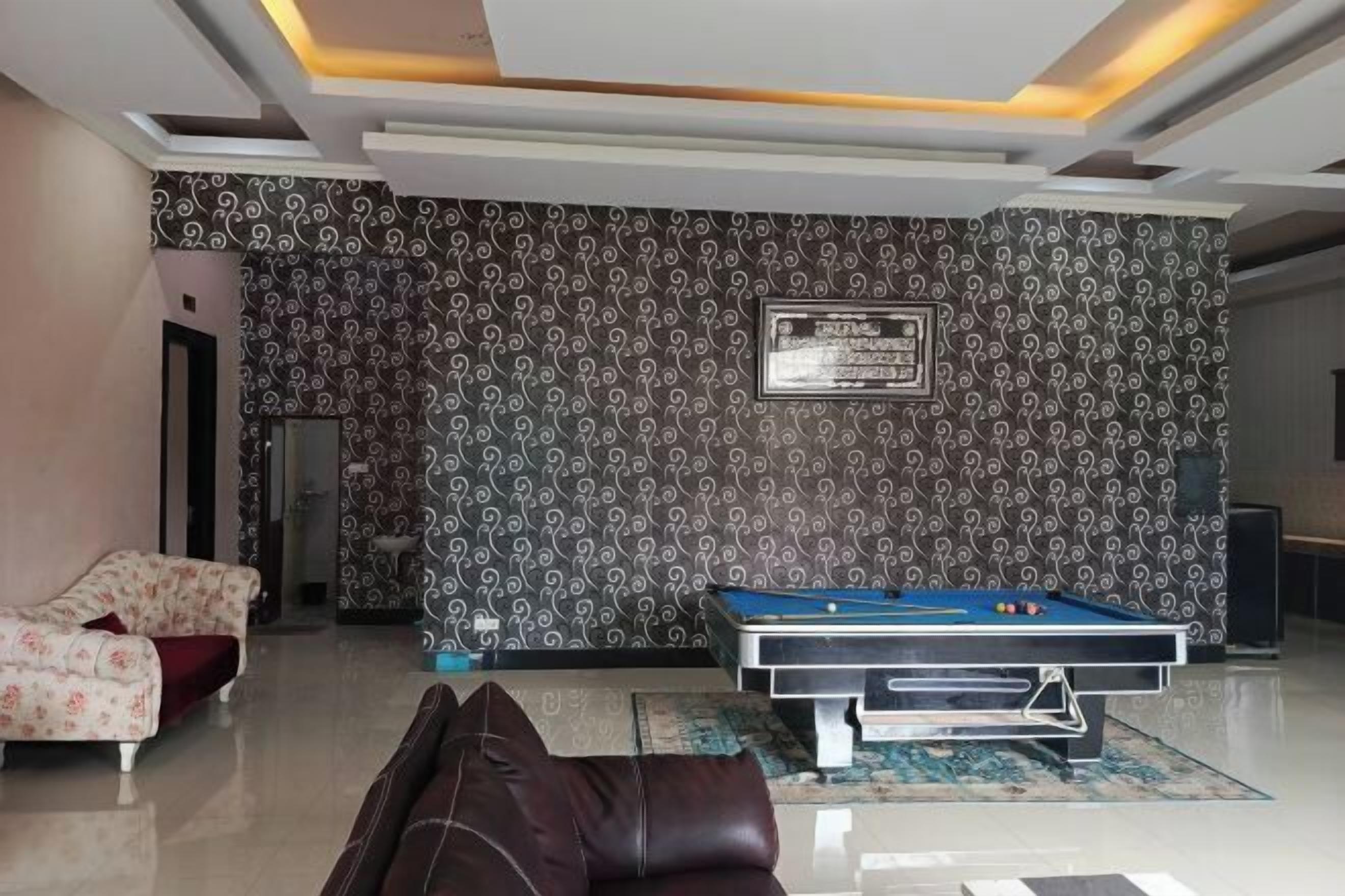 A modern living room with a pool table, a sofa, and a patterned wall.