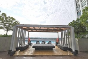 An outdoor seating area with a pergola, chairs, and a view of the water. - Bukit Indah Near Aeon and Legoland Johor with Netflix (Johor Bahru)