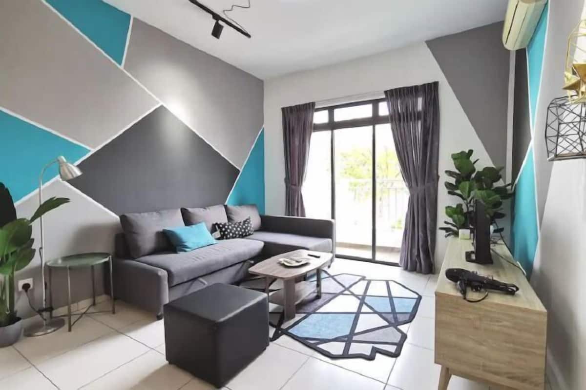 A modern living room with a sofa, ottoman, coffee table, and a geometric rug.