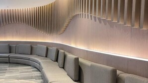 A modern, curved seating area with a wooden wall and recessed lighting. - Hannah's Crib at Shore Residences with Balcony and Pool View (Pasay)