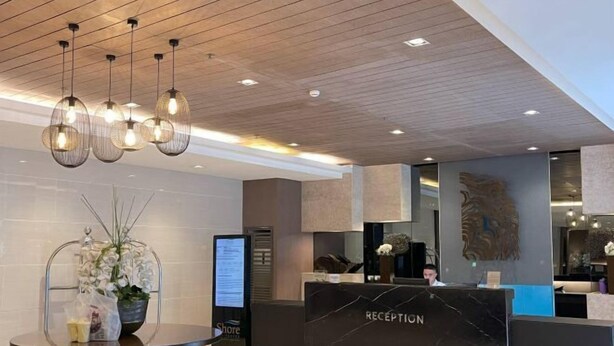 A reception area with a marble counter, overhead lighting, and a digital screen. - Hannah's Crib at Shore Residences with Balcony and Pool View (Pasay)