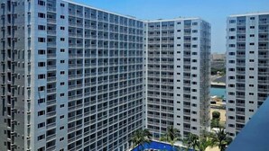 A high-rise building with multiple floors and balconies, featuring a grid-like window pattern. - Hannah's Crib at Shore Residences with Balcony and Pool View (Pasay)