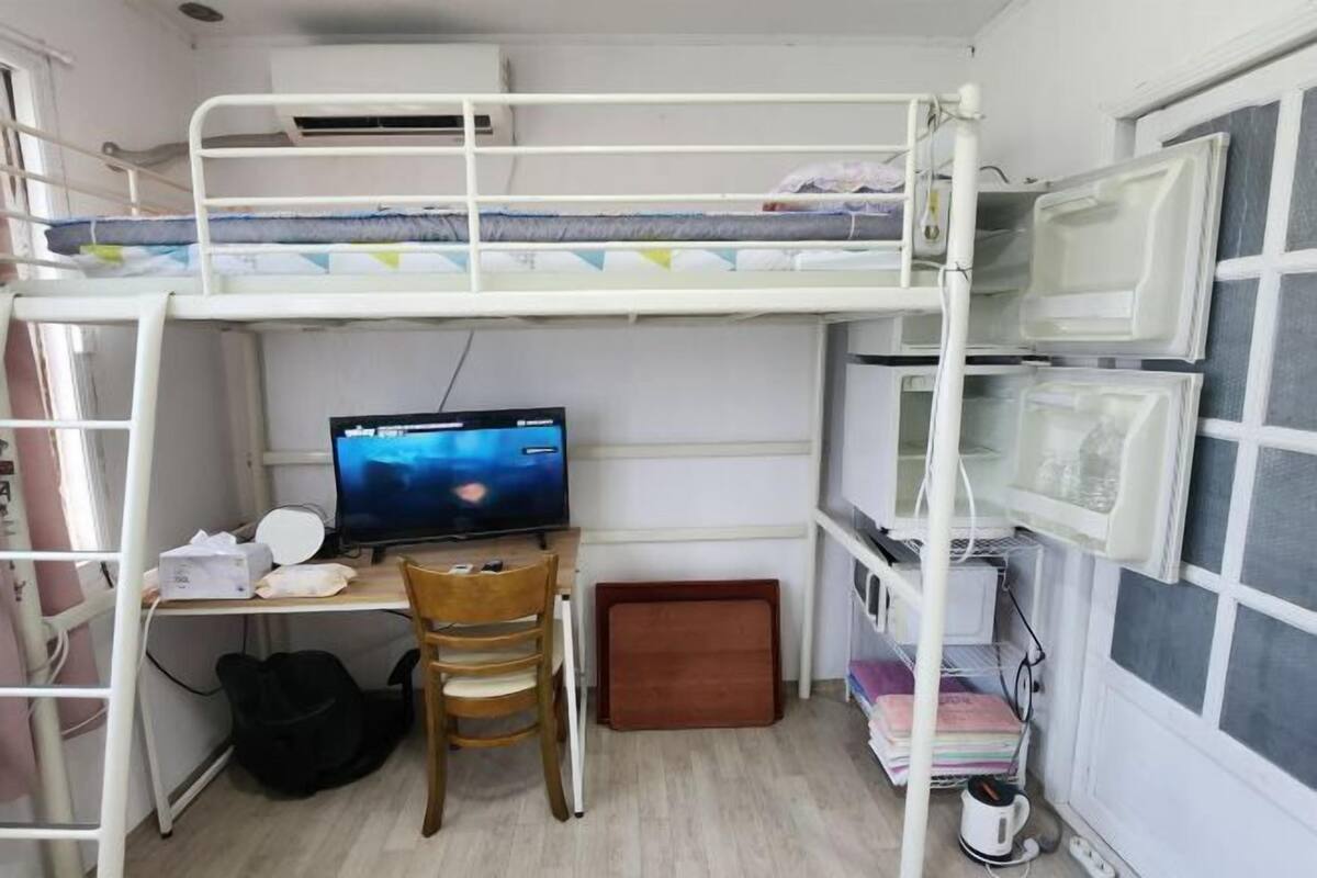 A bunk bed room with a desk, chair, computer, and shelves.