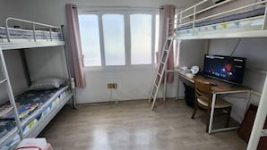 Une chambre de dortoir avec des lits superposés, un bureau avec un ordinateur et une fenêtre avec des rideaux.