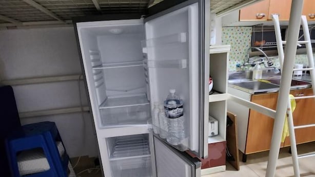 Une petite cuisine équipée d’un réfrigérateur, d’un évier et d’un tabouret.
