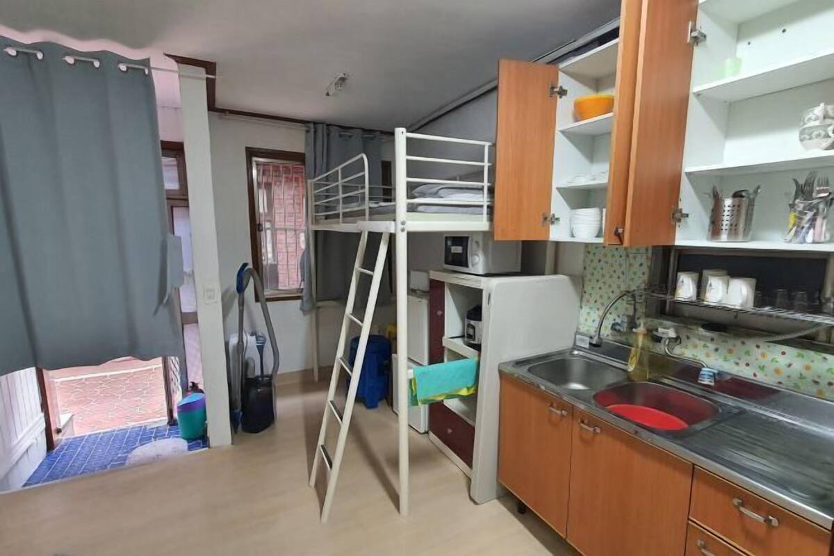 A compact kitchen with a sink, cabinets, and a bunk bed.