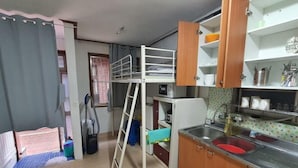 Une petite cuisine équipée d’un évier, de placards et d’un lit superposé.