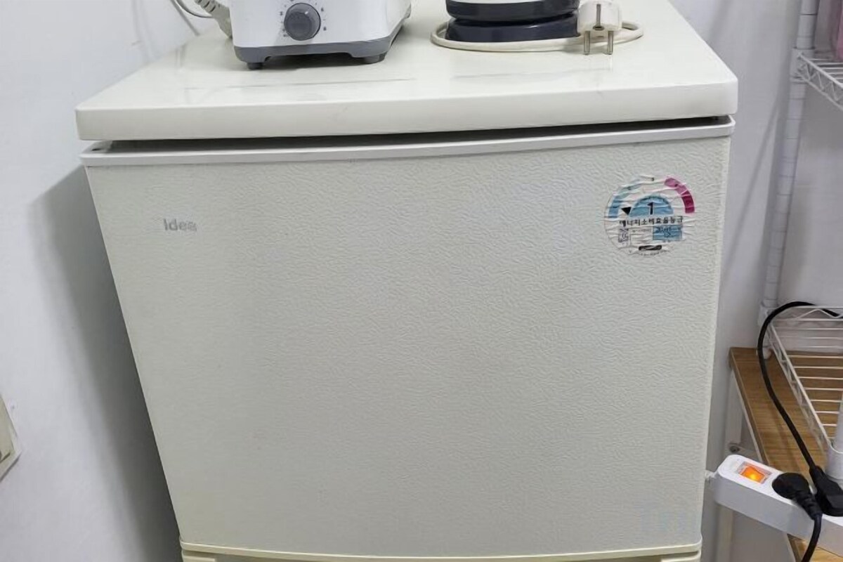 A compact refrigerator with a control panel and a logo sticker on the door.