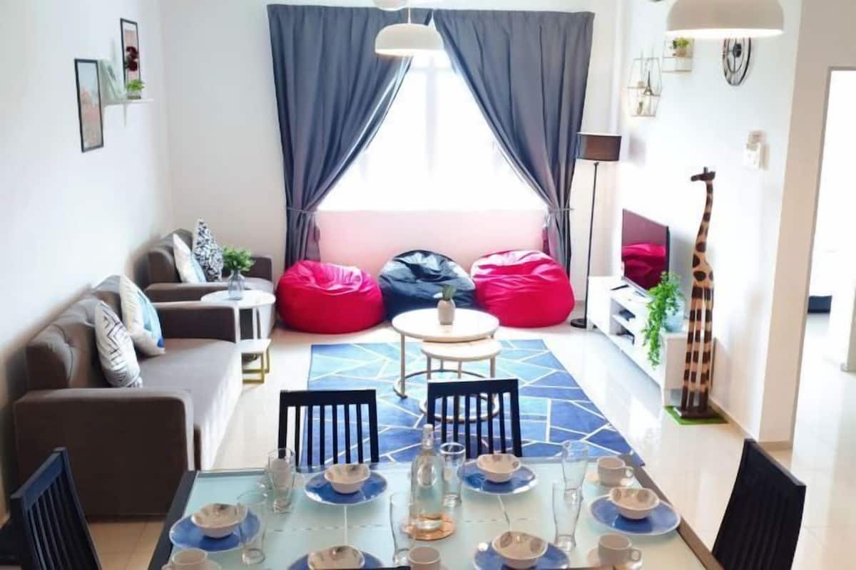 A modern living room with a glass dining table set for four, a sofa, a small round table, and a giraffe statue.