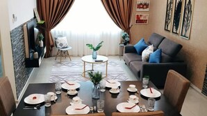 Un coin repas avec une table dressée pour quatre personnes, un canapé et une petite table d’appoint agrémentée d’une plante.