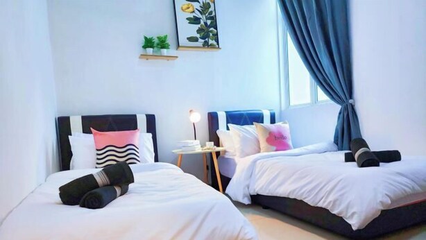 Une chambre d’hôtel avec deux lits, une petite table avec une lampe et une fenêtre avec des rideaux.